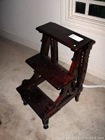 Angled view showing the side and front of the mahogany library stairs including two steps and spindle legs.