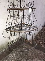 Front angle view showing middle and lower shelves of the corner rack against a stucco wall