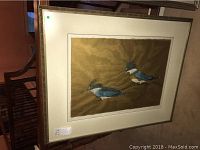 Framed print showing two birds on a golden-brown background with a white mat and a silver frame.
