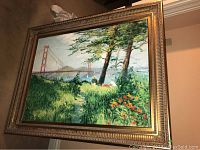 Framed oil painting showing Golden Gate Bridge in background with trees and two seated women in foreground plus flowers.