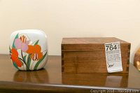 Porcelain vase with colorful floral design and wooden box on a wooden shelf