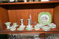 Full set of green jasperware items on wooden shelf including plate, candle holders, trinket boxes, vase, and more.