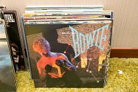 Stack of LPs with a David Bowie album front cover visible, featuring a shirtless Bowie and constellation graphics