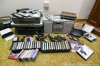 Overall lot showing all electronics, audio cassettes, remotes and cables arranged on carpet