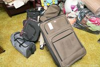 View of all luggage included in lot including brown suitcase, gray duffel, and black bags