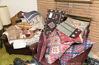 Photo showing an armchair and loveseat covered with decorative pillows, pillow shams, and throws in southwestern styles and patterns.
