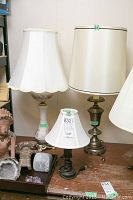 Three table lamps of different sizes and styles placed together on a table, showing shades and bases