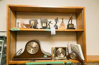 Shelving unit with the clocks on bottom shelves and trophies on upper shelf.