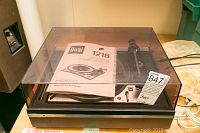 Overview of Dual 1218 turntable with clear dust cover and instruction manual on top