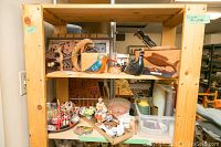 Shelf showing multiple decorative items including wood birds, wood carved panels, and figurines.