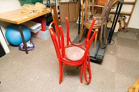 Two red painted wood chairs stacked upside down, showing curved backs and legs.