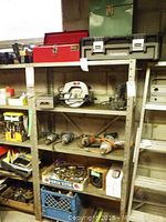 Shelf with power tools including Craftsman circular saw, sander, Black & Decker drill, tool boxes and clamps