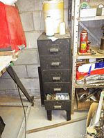 Full view of metal cabinet with drawers, showing wear and rust with spools of string on top.