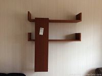 Three teak veneer floating shelves mounted on a wall, showing the overall design and layout with an asymmetrical style and visible scratches.