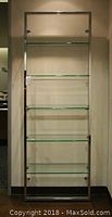 Full view of one glass shelving unit mounted on wall showing five shelves in chrome frame