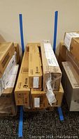 Photo showing multiple Xerox branded toner cartridge boxes stacked and wrapped partially in plastic on carpeted floor.
