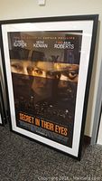 Full view of framed movie poster 'Secret In Their Eyes' showing actor faces, title and black frame.