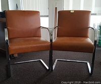 Front view of two brown leather office chairs with chrome base.