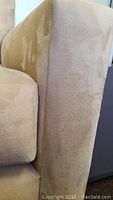 Close-up of sofa arm with visible wear and discoloration on microfiber fabric.