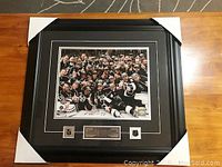 Framed 2012 LA Kings team photo celebrating Stanley Cup championship on ice with protective corner covers.