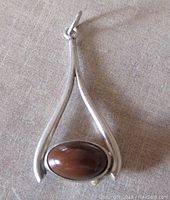 Front view of the pendant showing the brown stone set within the polished sterling silver frame with a tapered, open design.