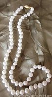Full view of 17.5-inch pearl strand on fabric background showing clasp and overall length