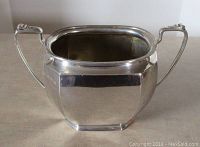 Front view of vintage sterling silver bowl with two handles on cloth surface.