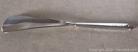 Full length view of vintage sterling silver shoe horn showing smooth blade and engraved handle.
