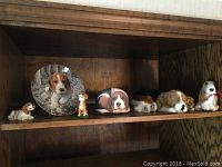 Shelf view showing seven dog figurines and plush toys along with beagle motif decorative plate