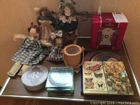 Full view of lot showing all items on wooden surface including rag dolls, coaster, stationery pads, and ornament box.