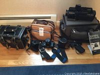 Overview of all items including the Panasonic video camera, GAF film camera, two camera cases, straps, lens covers, and the operating instructions.