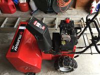 Side view of red Murray snow blower with black chute and tire chain on front tire