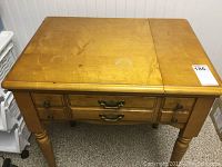Front angled view of hardwood sewing table showing top surface, drawers, and legs.
