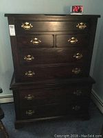 Full view of the tall hardwood dresser showing its overall shape and structure with brass handles on multiple drawers.