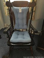 Front view of wooden rocking chair with blue cushion on tufted seat and back.