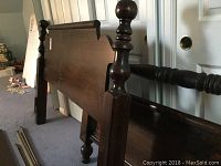 Full view of the dark wooden bed frame including headboard and footboard with cannonball style posts showing minor wear.