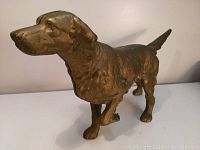 Front and side view of the brass English Setter doorstop showing detailed sculpting of dog's head, neck, and body.