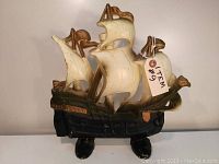 Full front view of cast iron ship doorstop showing overall shape, paint, and detailing with sails and flags.
