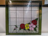 Full front image of the stained glass window showing the floral design with red, yellow, and pink flowers, and green border.