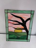 Front view of stained glass window showing full sunrise scene with tree and hills framed by green beveled glass border.