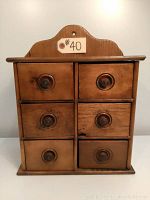 Front view of antique wooden spice cabinet with six drawers, showing wood finish and drawer knob details.