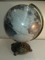 Front view of globe showing Western Hemisphere, metal meridian and decorative base