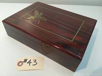 Closed polished rosewood jewellery box with brass inlay of flying bird design on lid