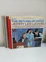 Front view of 9 vinyl LP records stacked, front album is The Return of Rock by Jerry Lee Lewis showing colorful mid-century photo cover.