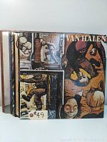 Nine vinyl LP records stacked with visible album artwork, one marked with #49 tag including Van Halen and Fair Warning albums.
