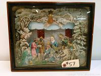 Front view of vintage religious nativity diorama inside wooden glass-front case showing all figures and background.