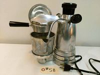 Front angle view of the polished cast aluminum cappuccino maker with frothing pitcher attached and electric cord visible.