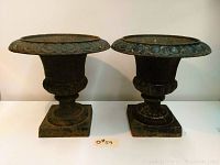 Two matching cast iron urns side by side showing overall shape and size.
