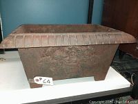 Front view of rectangular planter showing floral basket relief and fluted rim