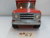 Front view of red vintage Tonka dump truck showing grill, headlights, and front bumper with 'Tonka' embossing.